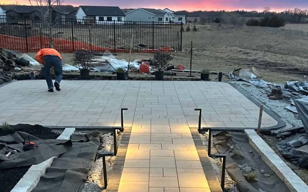 Landscape lighting installed along a paver patio at dusk